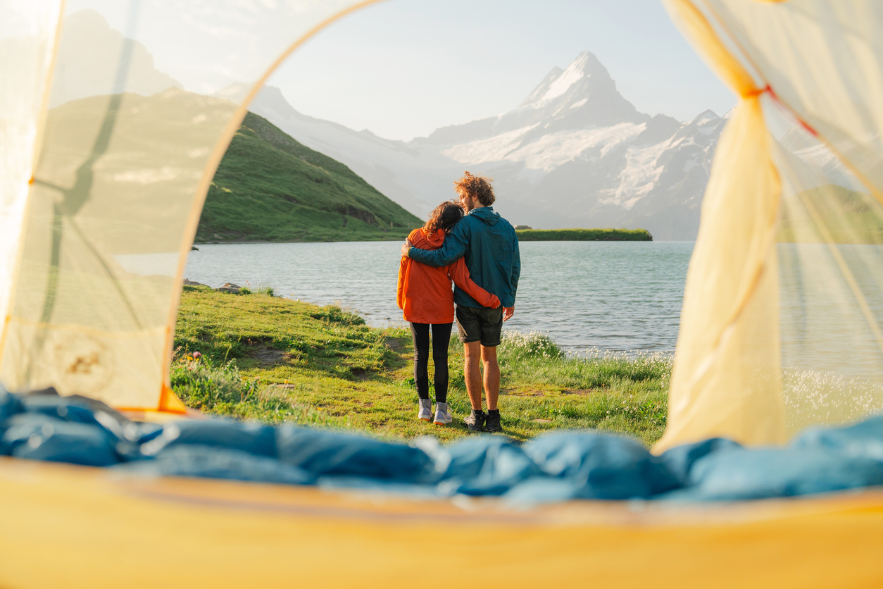 Man and woman camping near the lake in Swiss Alps with the tent