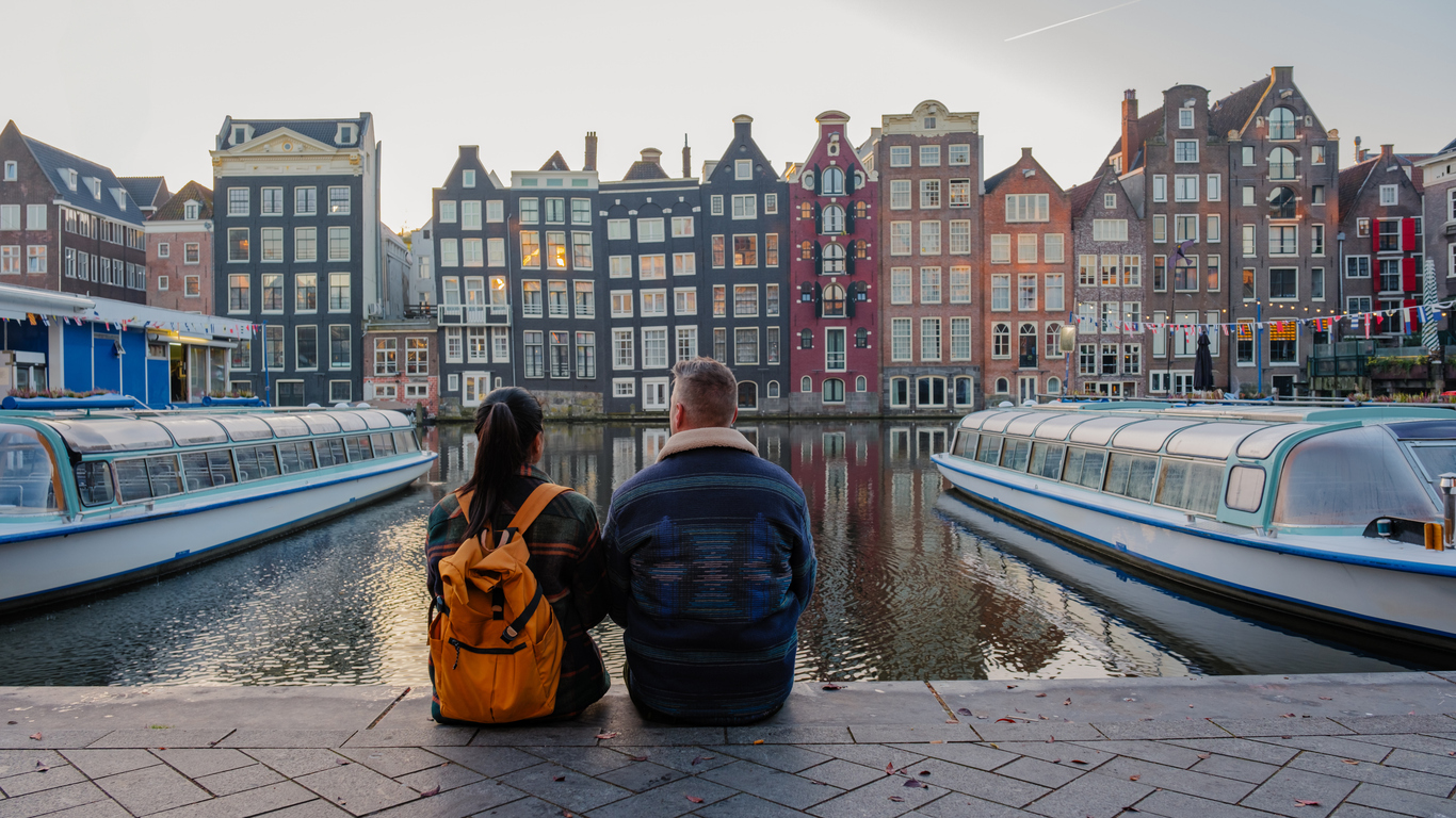 Couple enjoying a tranquil autumn evening by the canal in Amsterdam, Netherlands